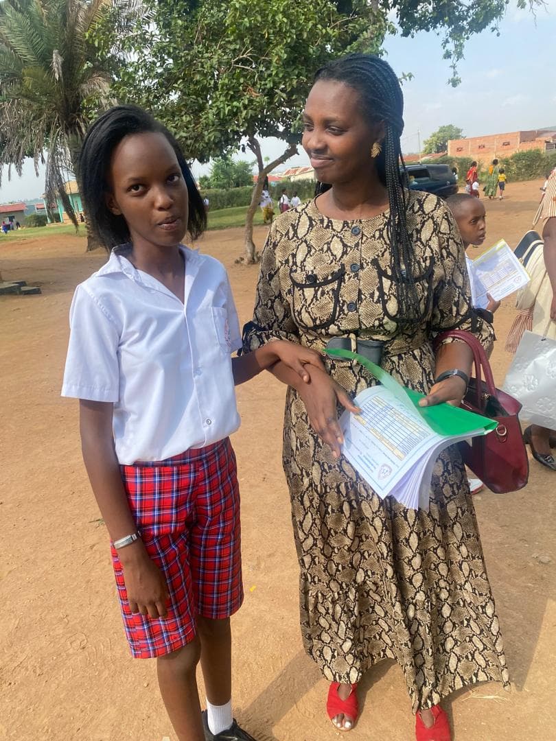 Jasmine in her school uniform standing beside a woman holding her school papers