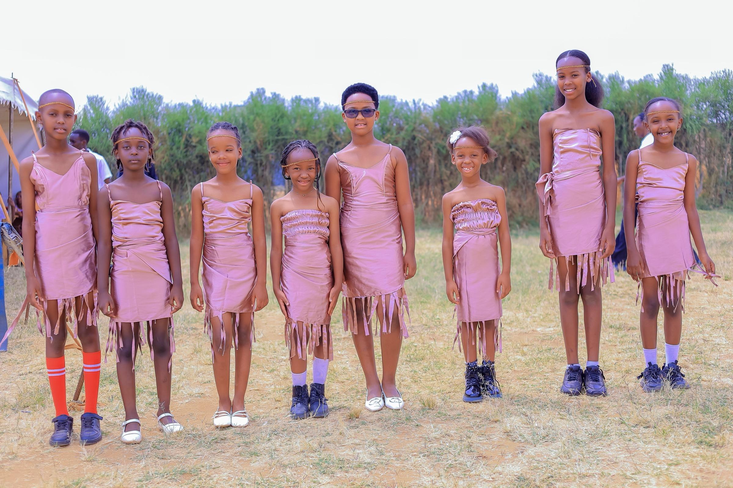 Eight girls in matching dance costumes lined up on the school field