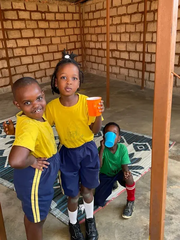 Three young children holding cups at break time