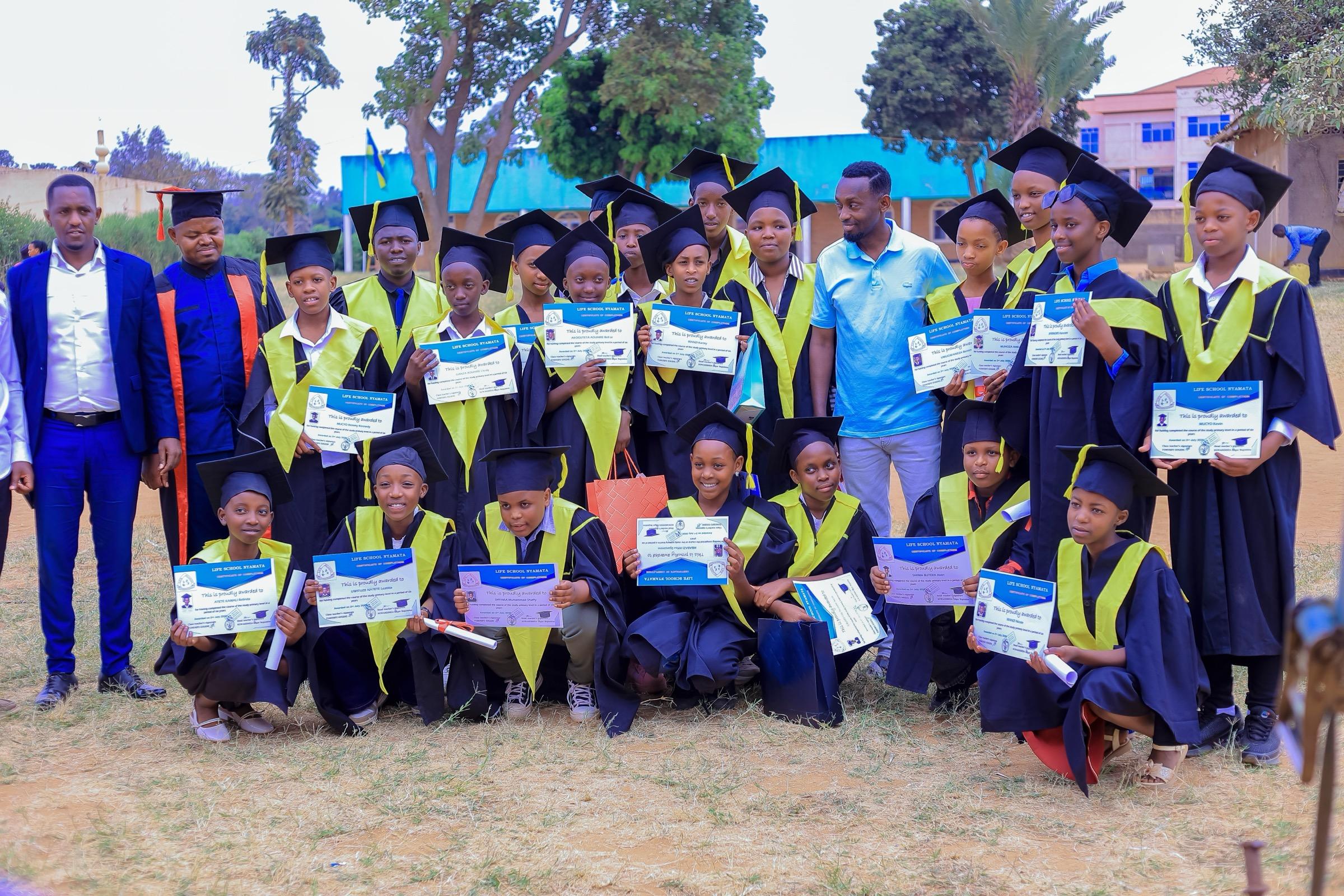 Graduates in caps and gowns holding their certificates alongside their teachers