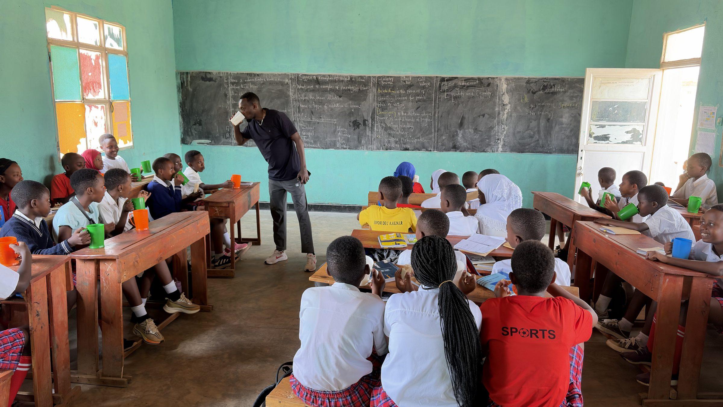 A full classroom of pupils eating at their desks, seen from the back