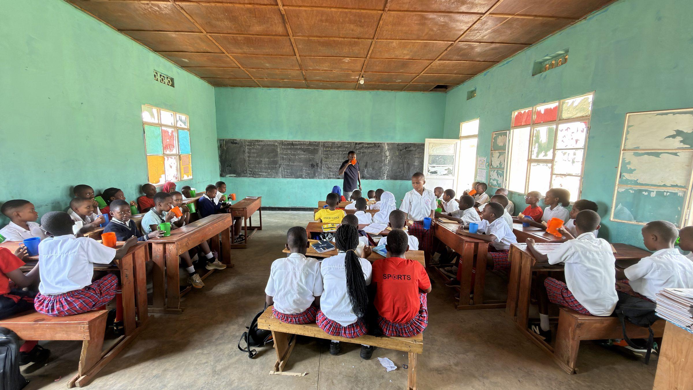 Rows of pupils eating at desks, seen from the classroom doorway