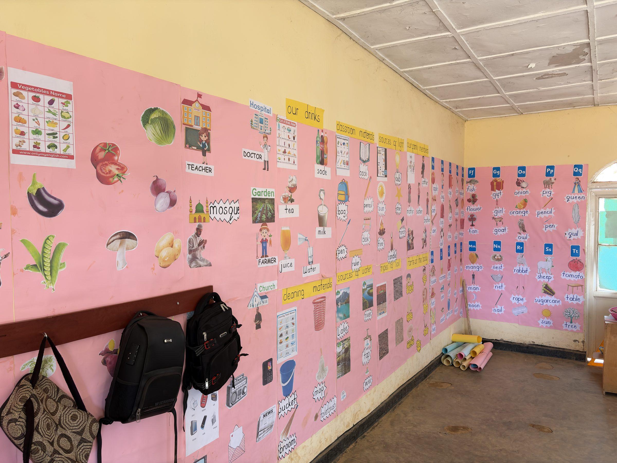 A pink classroom wall covered in labelled pictures of foods and everyday objects
