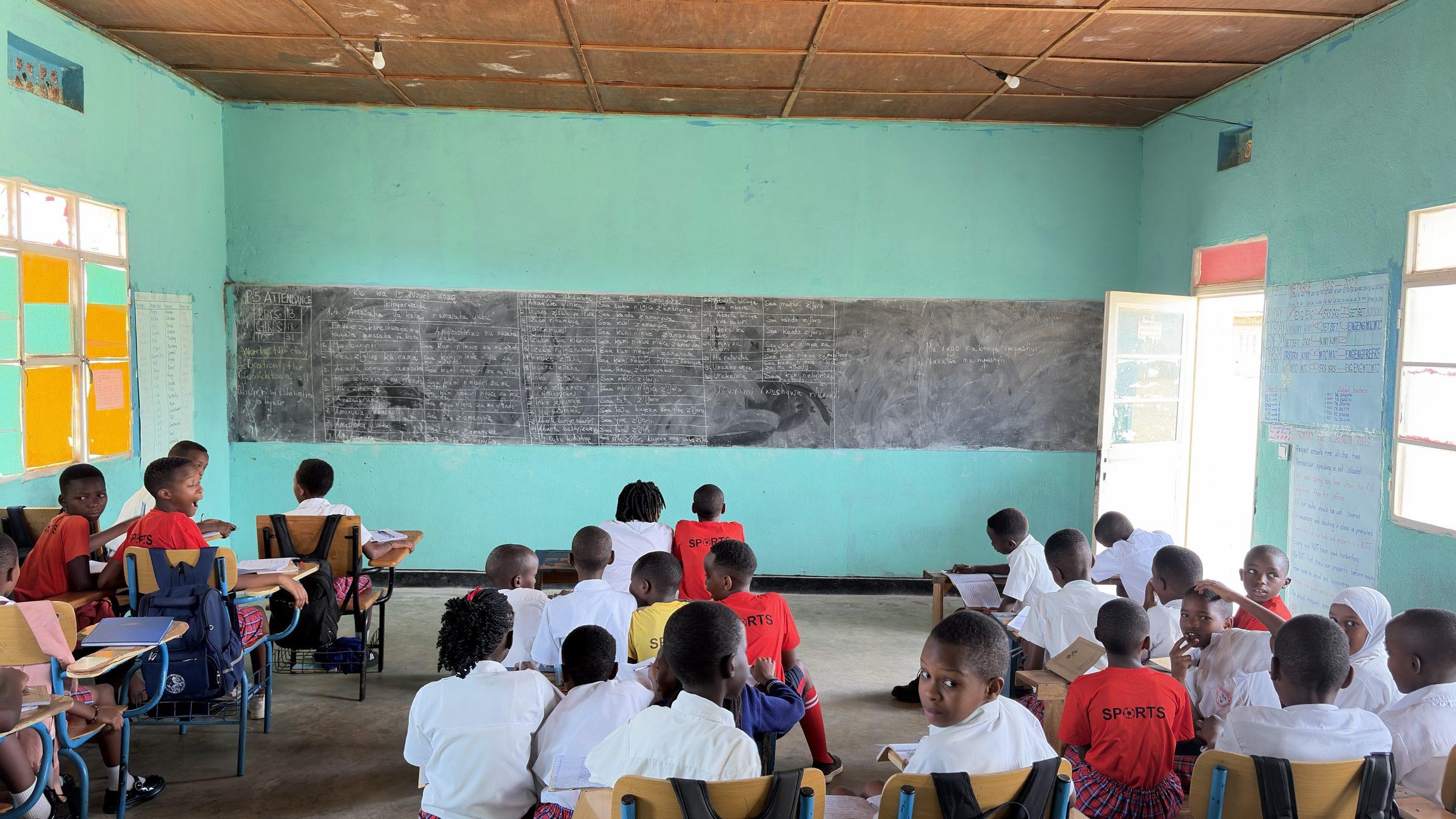 Pupils at desks facing a long chalkboard in a green classroom