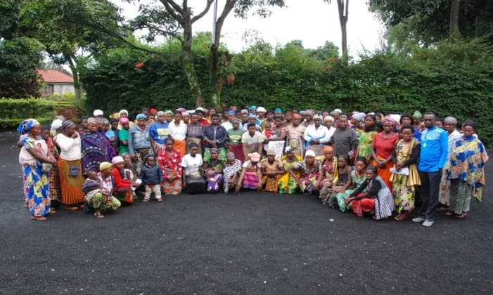 A large group of women in patterned wraps standing together outdoors after a training