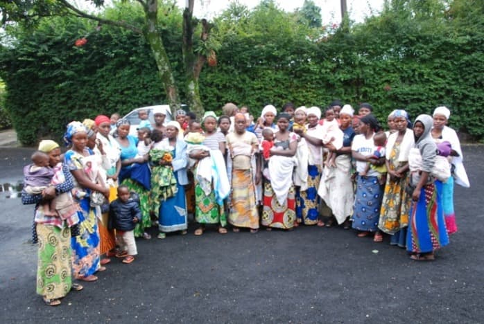 A group of women carrying babies on their backs, standing together outdoors